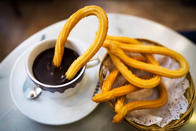 Traditional chocolate con churros served in Madrid, with churros dipped into a cup of thick hot chocolate.