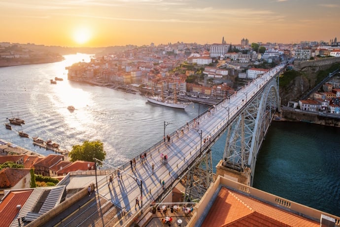 Pedestrians crossing the iconic Dom Luís I Bridge at sunset, with sweeping views over the Douro and the old town.