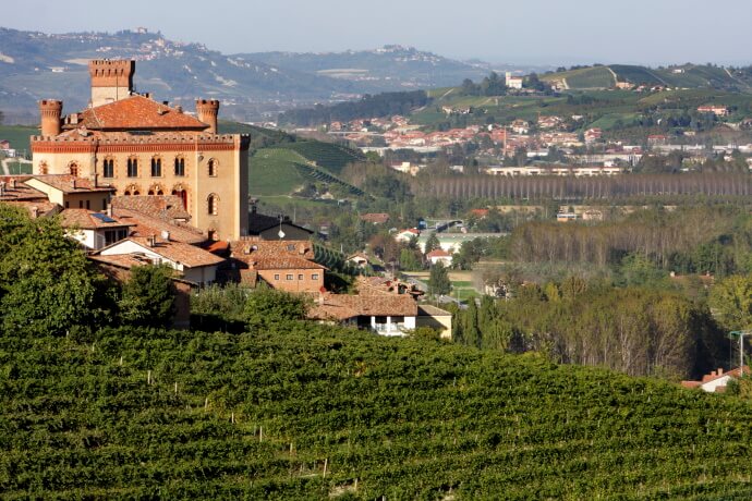 Scenic view of a historic castle surrounded by vineyards in the rolling hills of Italy’s Piedmont wine region