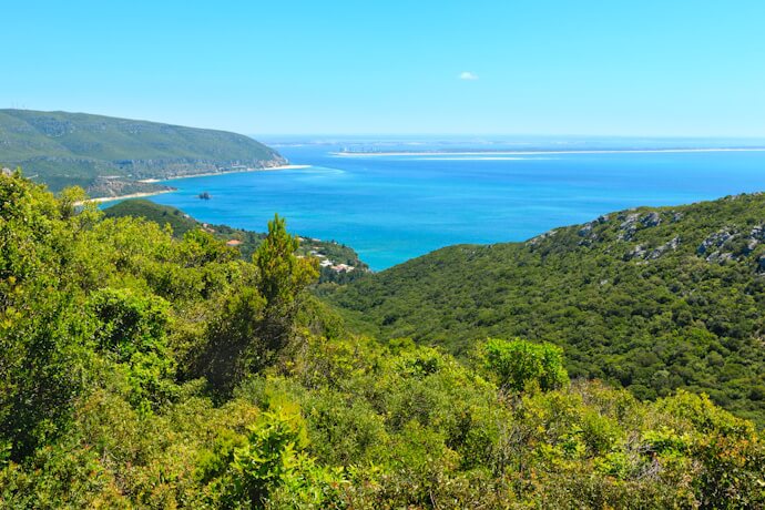 Arrábida Nature Park landscape where lush green hills tumble down to turquoise waters and sandy beaches.