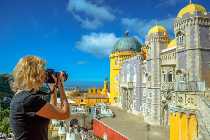 Pena Palace painted in vivid colors sits atop lush hills, blending Romantic architecture with stunning mountain views.