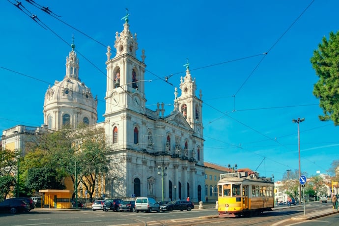 Yellow tram passing Basílica da Estrela in Lisbon