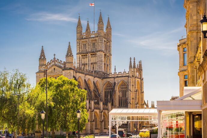 Bath Abbey rising above Baths historic center, framed by trees and Georgian buildings