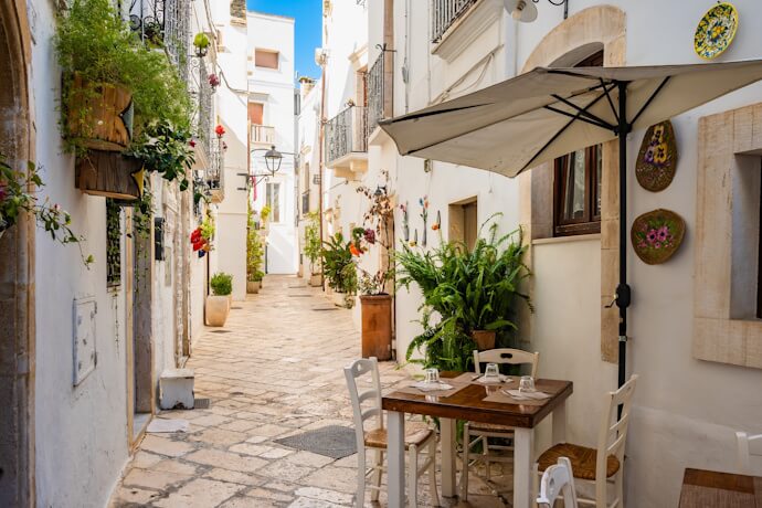 Whitewashed lane with flowers and outdoor dining in Locorotondo.
