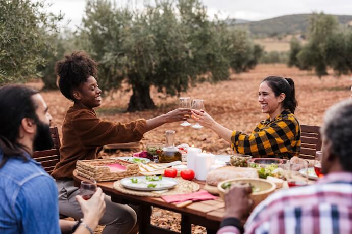 Outdoor meal and wine shared among olive groves.