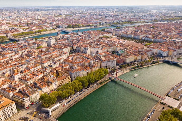 Panoramic aerial view of Lyon’s rivers, bridges, and terracotta rooftops stretching across the city.