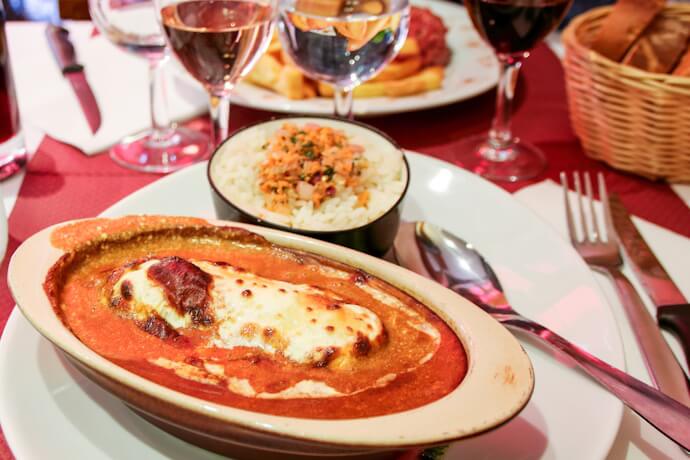 Traditional Lyonnais dish served with melted cheese, rice, and wine in a classic local bistro setting.