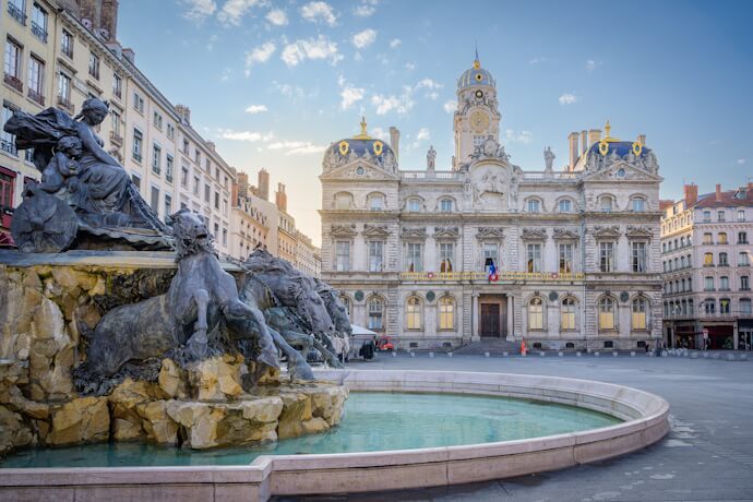 Historic fountain and ornate city hall building in Lyon’s grand central square.