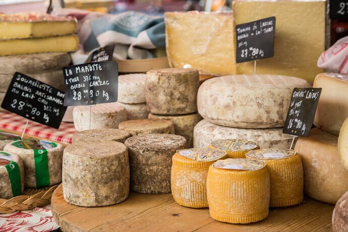 A variety of artisanal French cheeses displayed on a wooden counter at a local market