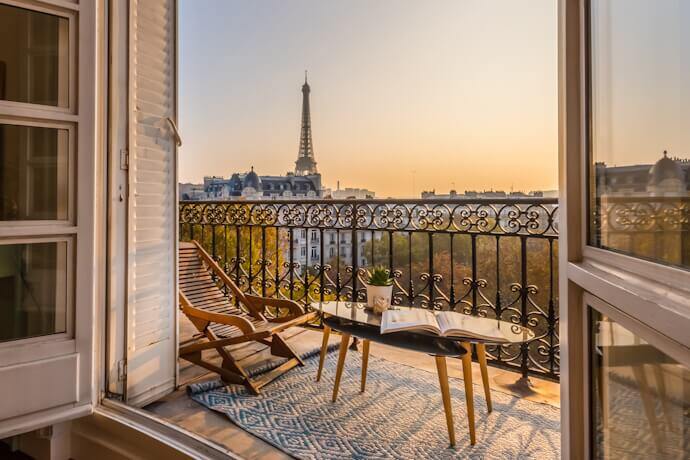 A cozy Parisian balcony with a view of the Eiffel Tower at sunset
