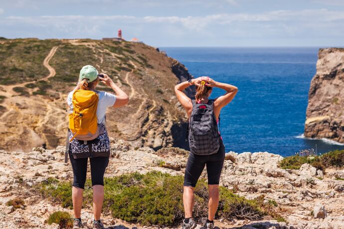Hikers exploring the rugged Algarve coastline in Portugal.