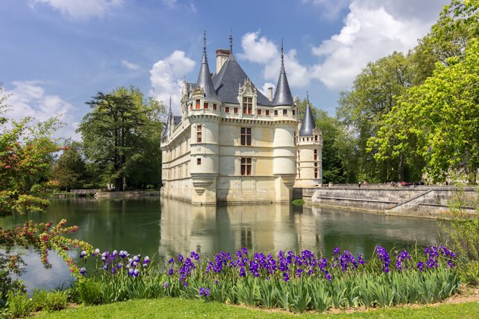 In the Loire Valley, France, Château d’Azay-le-Rideau sits on a mirror-still moat, with spring flowers and lawns brightening the scene.