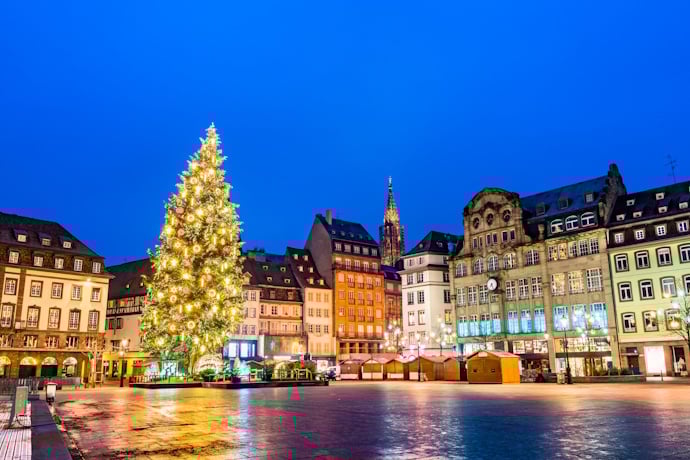 Christmas tree lights up the main square, framed by the city’s historic façades at blue hour, in Strasbourg.