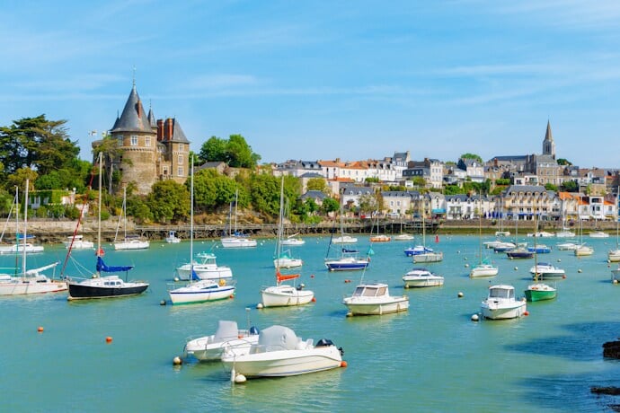 Harbor view of Pornic, France, with colorful boats, the medieval Château de Pornic, and historic seaside houses along the Atlantic coast