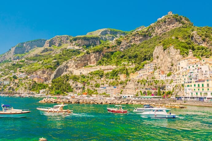 Colorful seaside village of Amalfi with boats in the harbor and steep cliffs along the Amalfi Coast, Italy.
