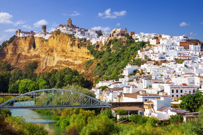 View of a whitewashed Andalusian town, Arcos de la Frontera, perched on a cliff above the river
