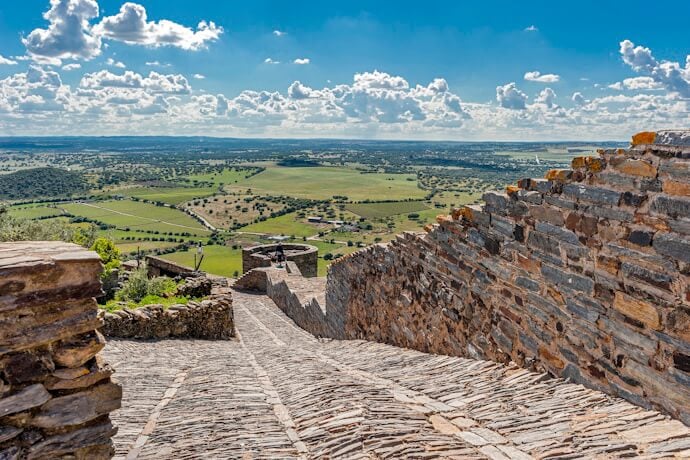Medieval paved wild stone road to the fortress and the city, with views of the vineyards, olive groves, and fields, in Monsaraz.